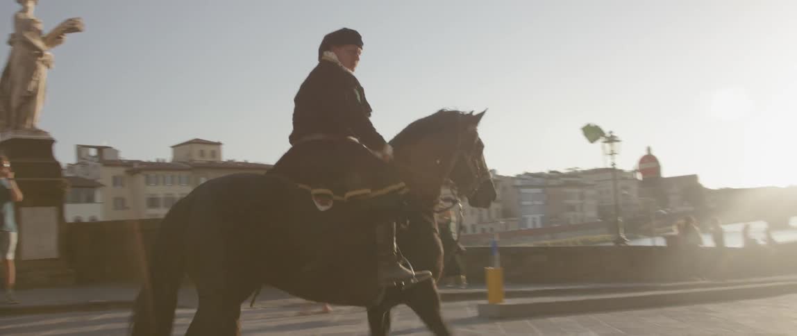 Person riding a high-stepping horse down a street