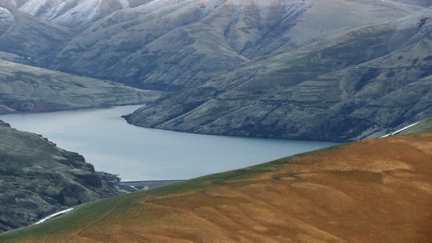 Lower Granite Dam on the Lower Snake River near Lewiston, Idaho is eclipsed by a tall hill at sunset in winter in this aerial