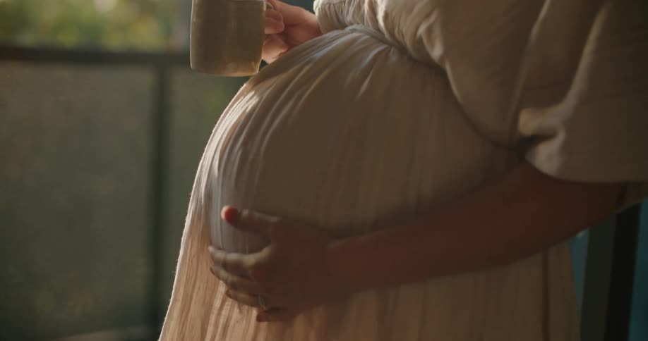 A pregnant woman is standing outdoors