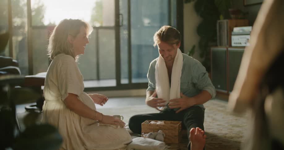 A couple sit on the carpet going through a box