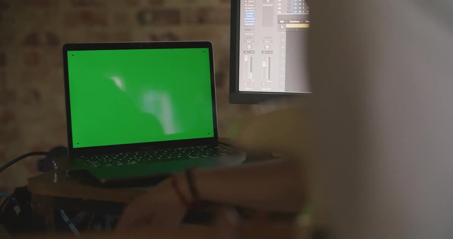 A person using a laptop and computer monitor at a desk