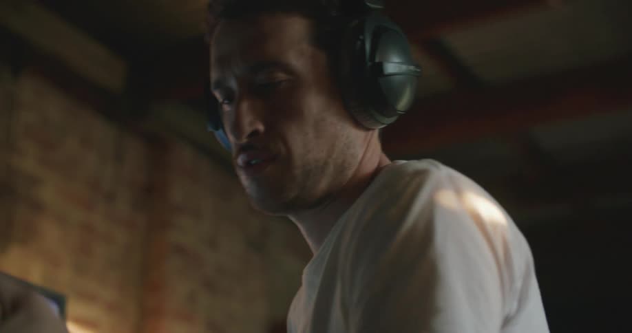 A man is playing guitar by the computer