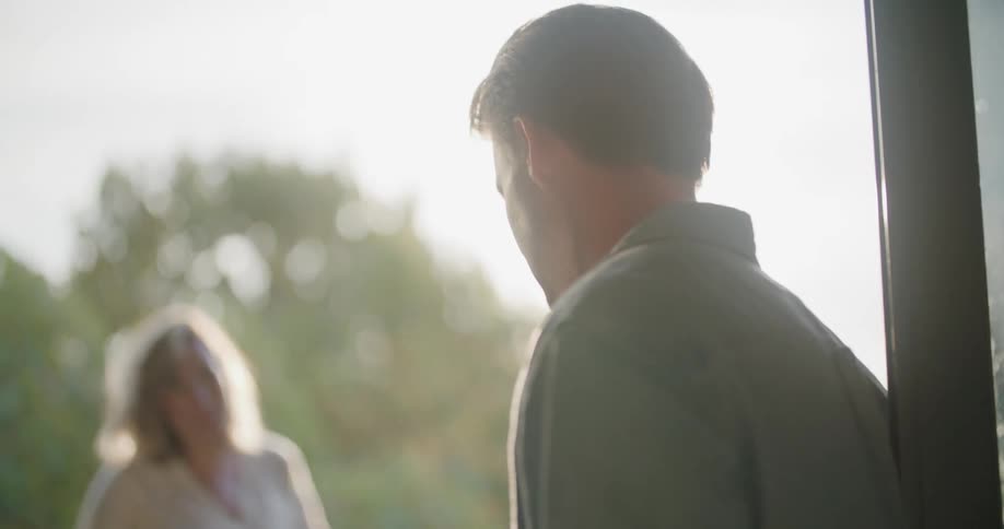 Pregnant couple drinking hot beverages on the balcony at sunset