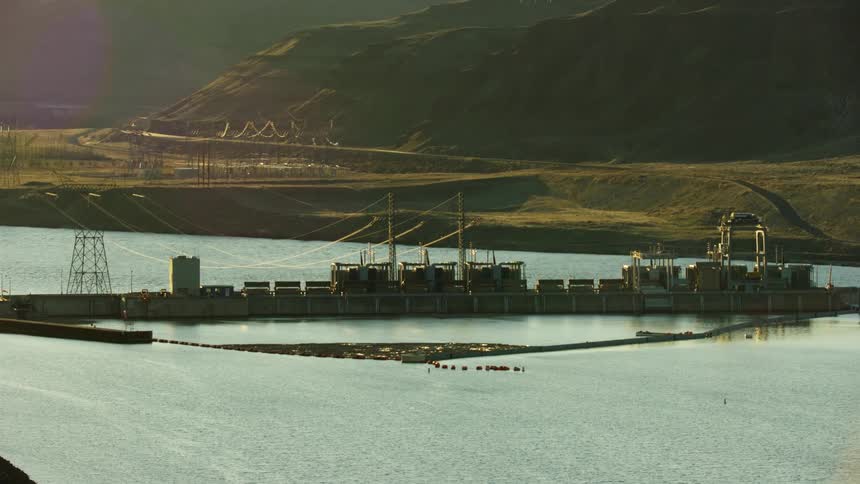 Low altitude dynamic zoom aerial of Little Goose Dam on the Lower Snake River with powerlines and the size of the dam visually communicated