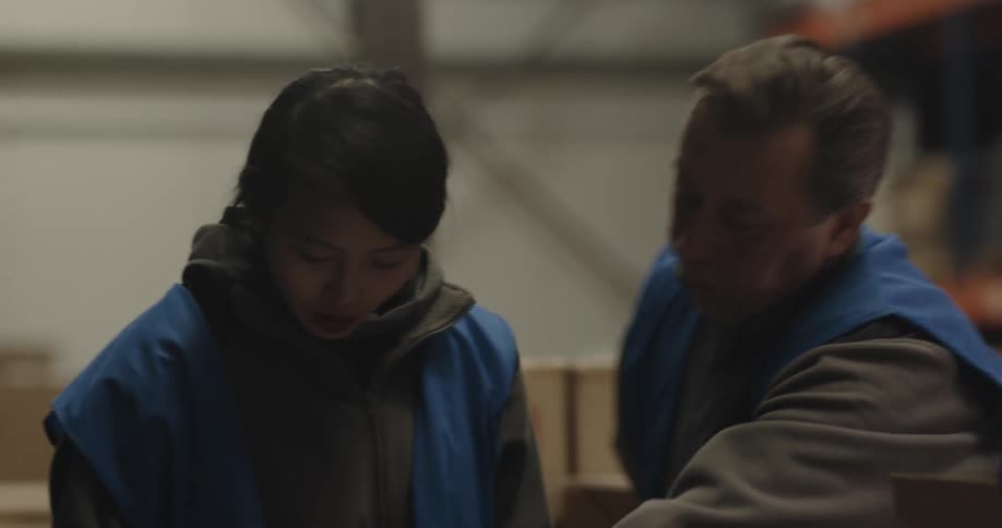 Two coworkers talking while boxing up things in a warehouse