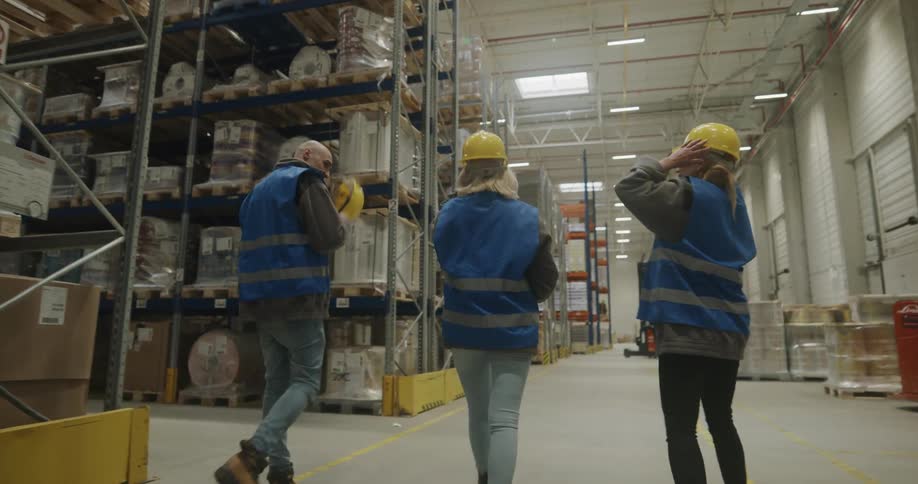 Coworkers talking and walking on the aisles of a warehouse