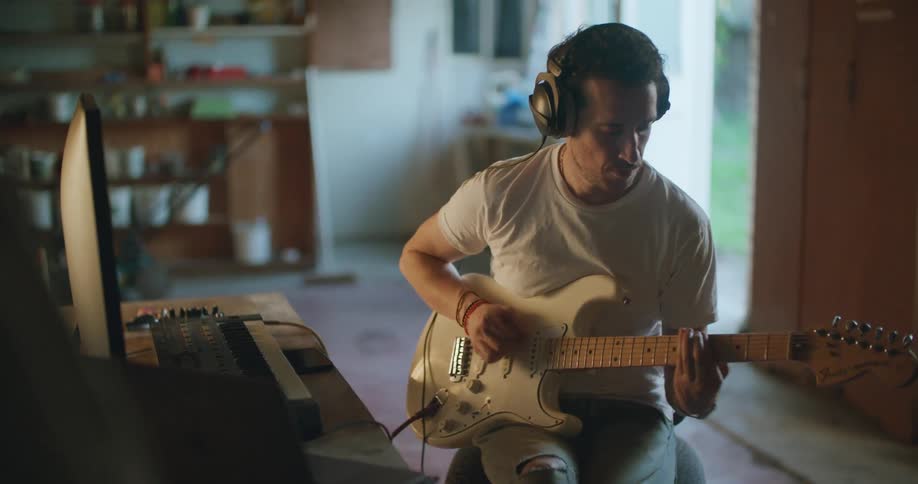 A man recording guitar with a computer