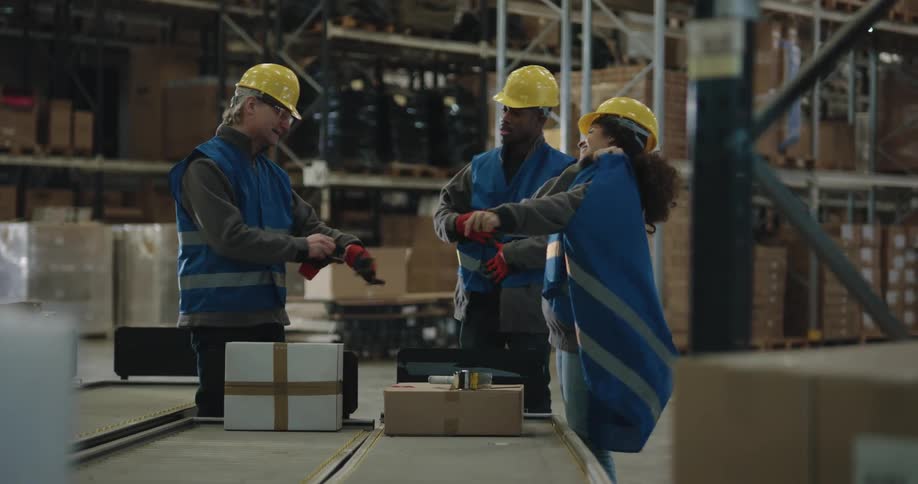 Employees on a warehouse wearing protective clothes and yellow hardhats