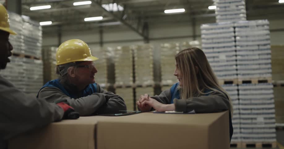 Three employees are talking together in a warehouse