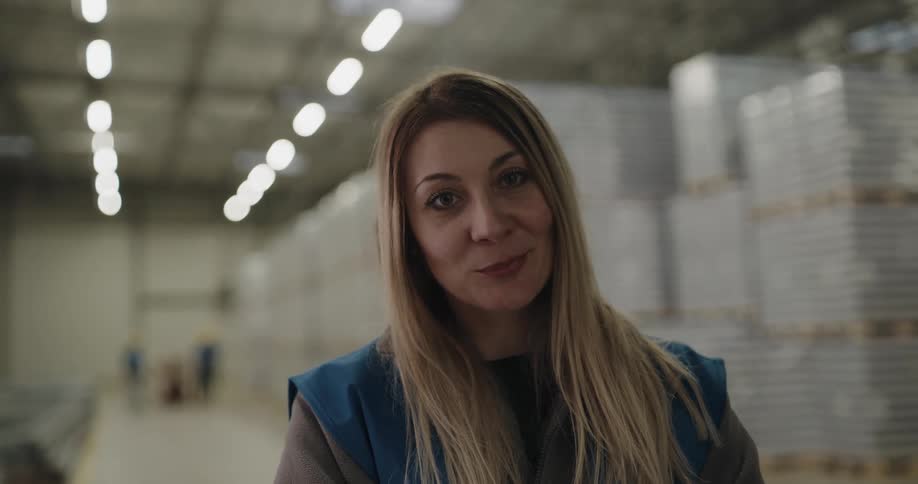 Blonde female worker looks at the camera smilingly in the warehouse