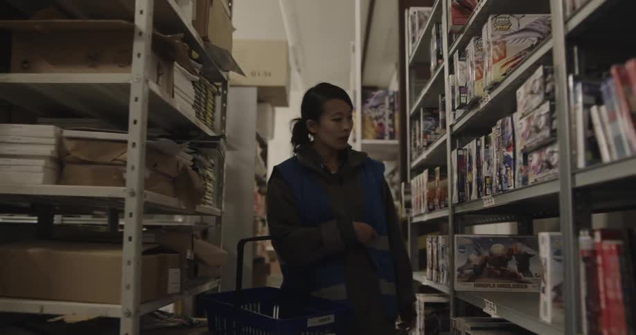 Woman working on a warehouse searchs for products in the shelves