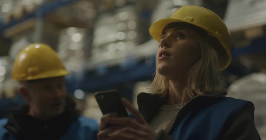 Wokrers in a warehouse wearing yellow hardhats checking inventory