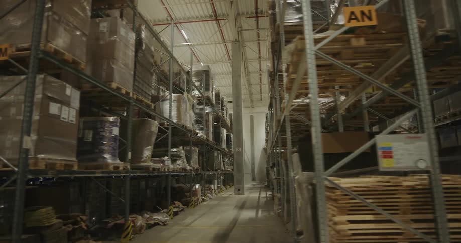Tall metal shelves stocked with goods in a large warehouse
