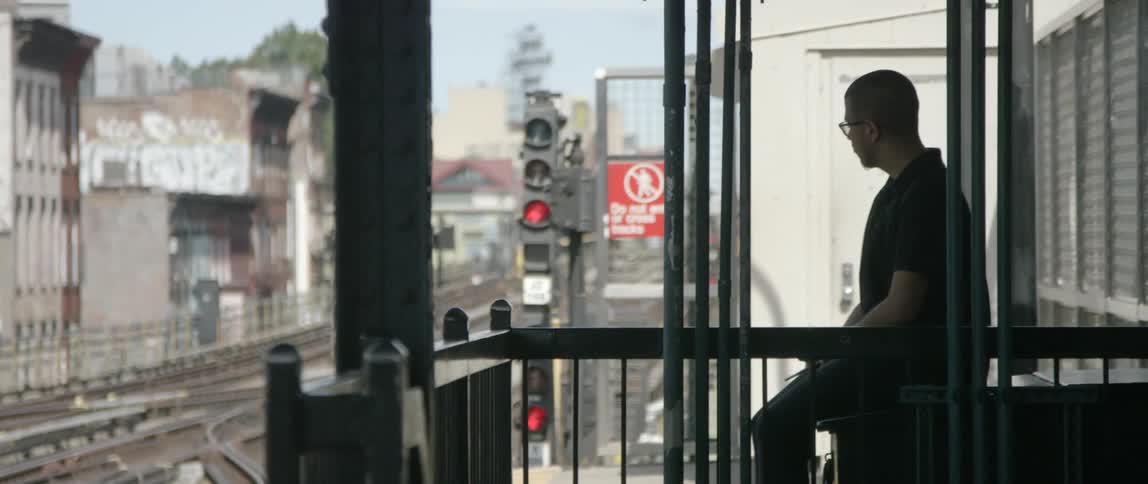 A man stands on a train platform waiting