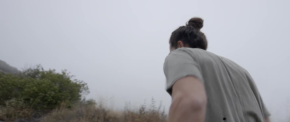 A man in a gray shirt runs up a hill