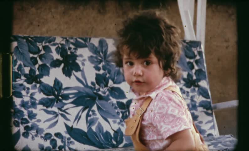 A toddler outside playing on a chair swing and a chair