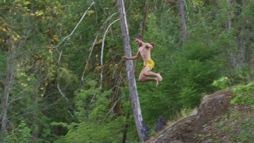 A man is jumping off a cliff and into the water
