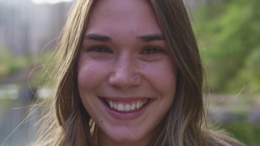 Girl with nose jewelry smiles broadly standing outdoors