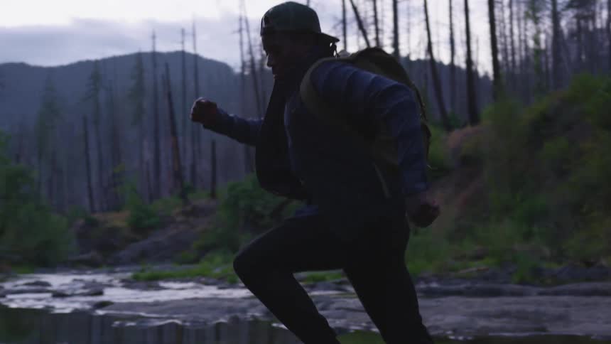 A man is jumping over the stream