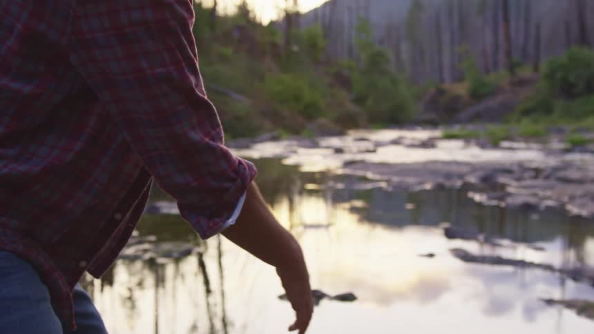 A man throws a stone skipping it on the pond