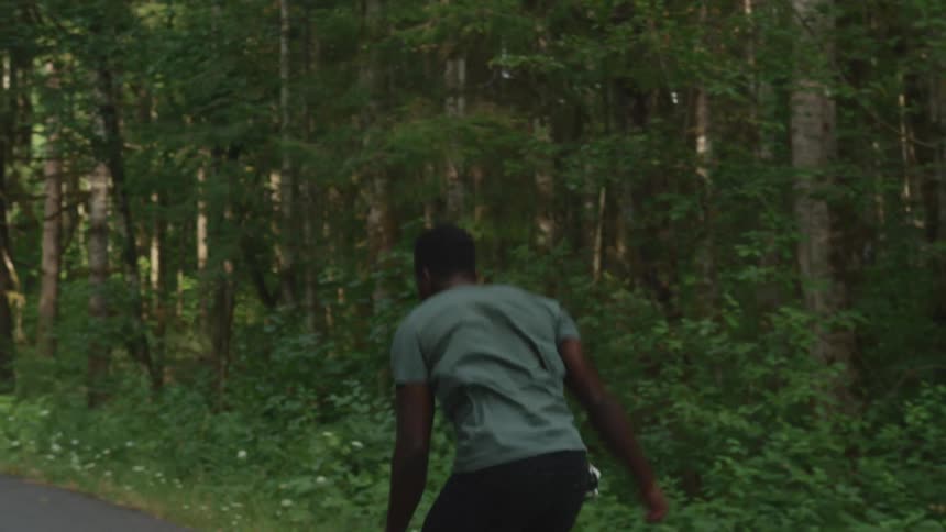 A man riding a skateboard through a forest