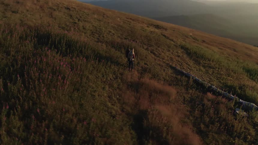 Couple of senior citizen standing on the slope of a mountain at sunset