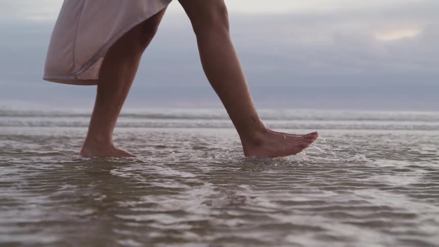 A woman is walking in the water on the beach