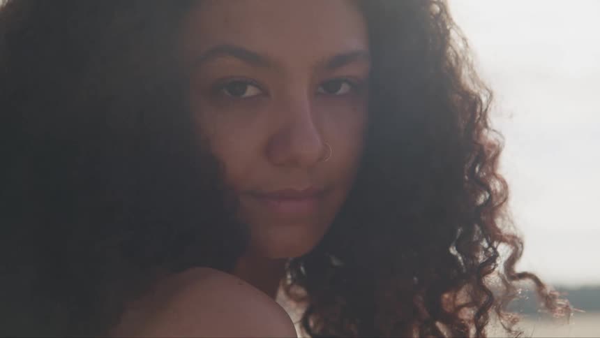 Young long haired woman standing outdoors looks up to the camera