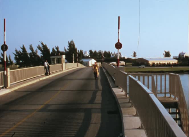 A girl is riding a bike over a bridge during the day