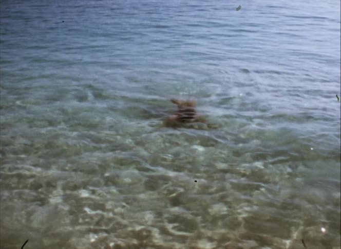A person is swimming underwater as the water ripples and reflects sunlight
