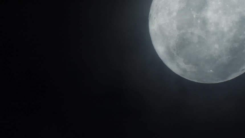 Clouds moving across the moon in the night sky