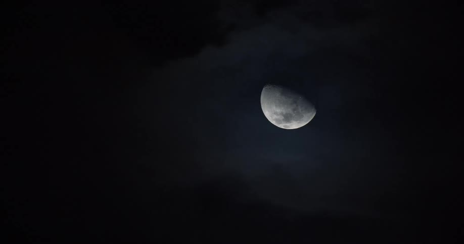 The moon hangs in the sky as dark clouds move by