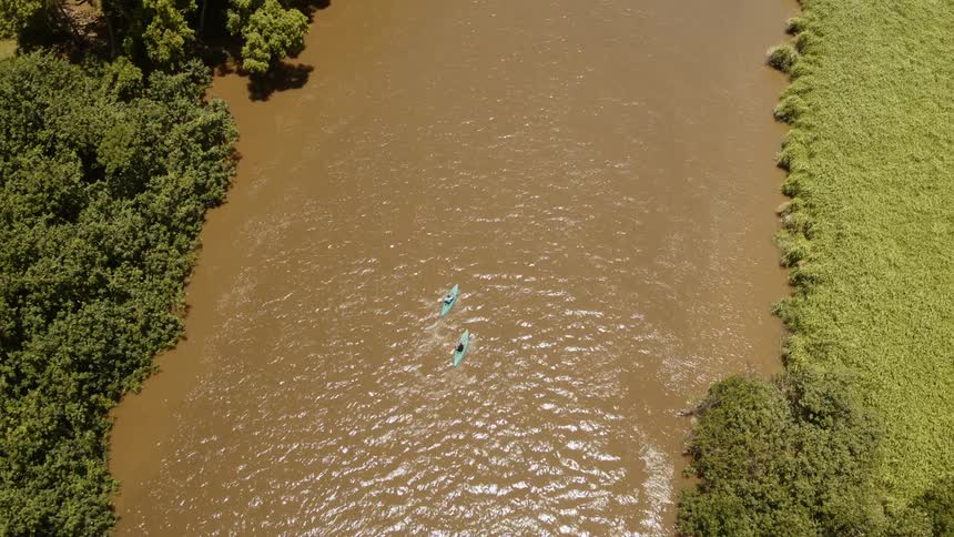 Two kayaks are paddled down a river