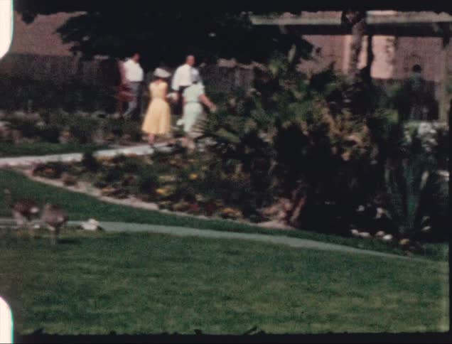 Two women walking on a path towards a building meet two men heading in the same direction on a sunny day
