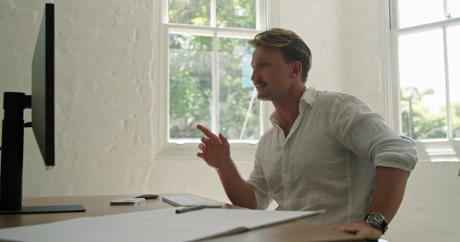 Man sitting in a desk at his home office talking on a video call in his computer