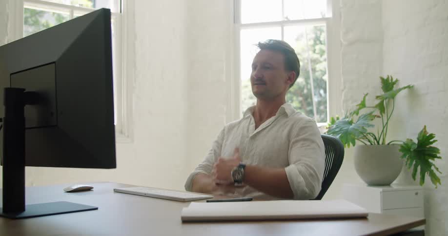 Man sitting in a desk at his home office talking on a video call in his computer