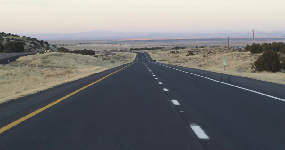 Cars drive down a highway through grasslands
