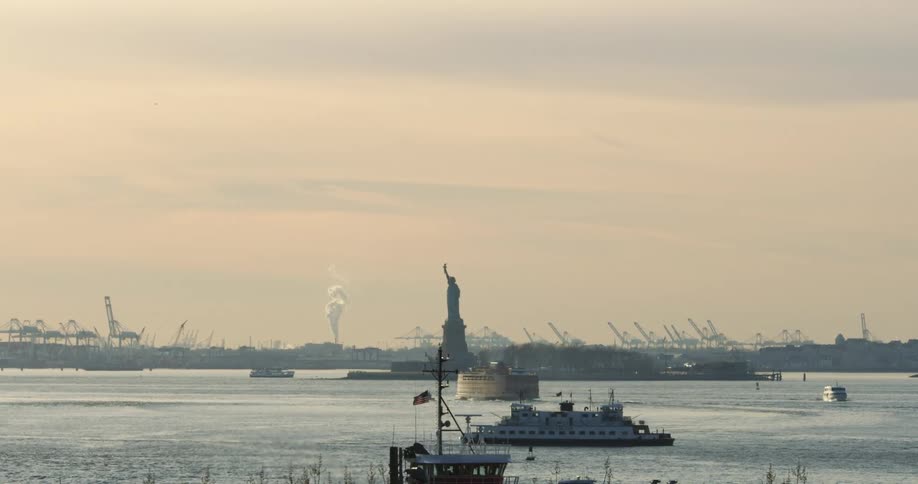 Boats cross the ocean in front of the statue of liberty