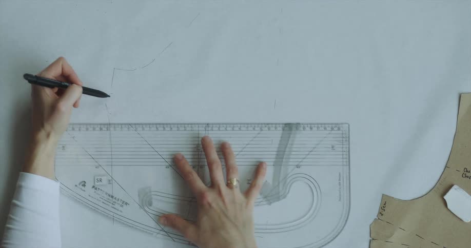 An architect uses a combination straight and curved ruler to draw lines on a large piece of paper