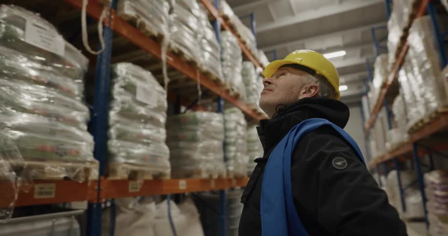 Warehouse worker inspecting the contents of a the pallets on the aisles