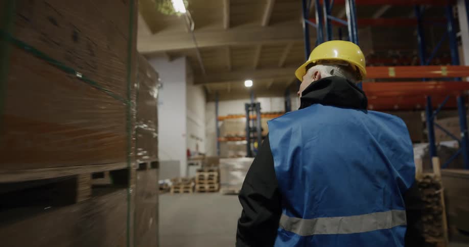 Warehouse worker walking between the aisles waving to coworkers