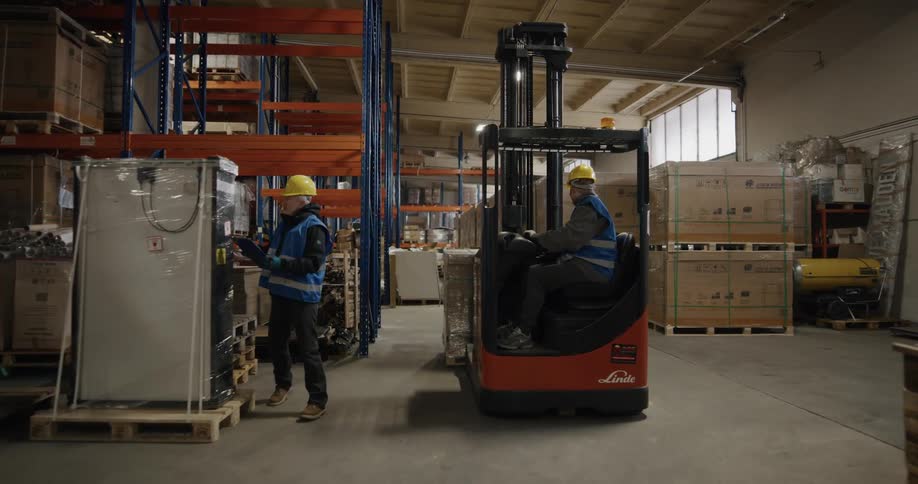 Workers in a warehouse driving a forklift