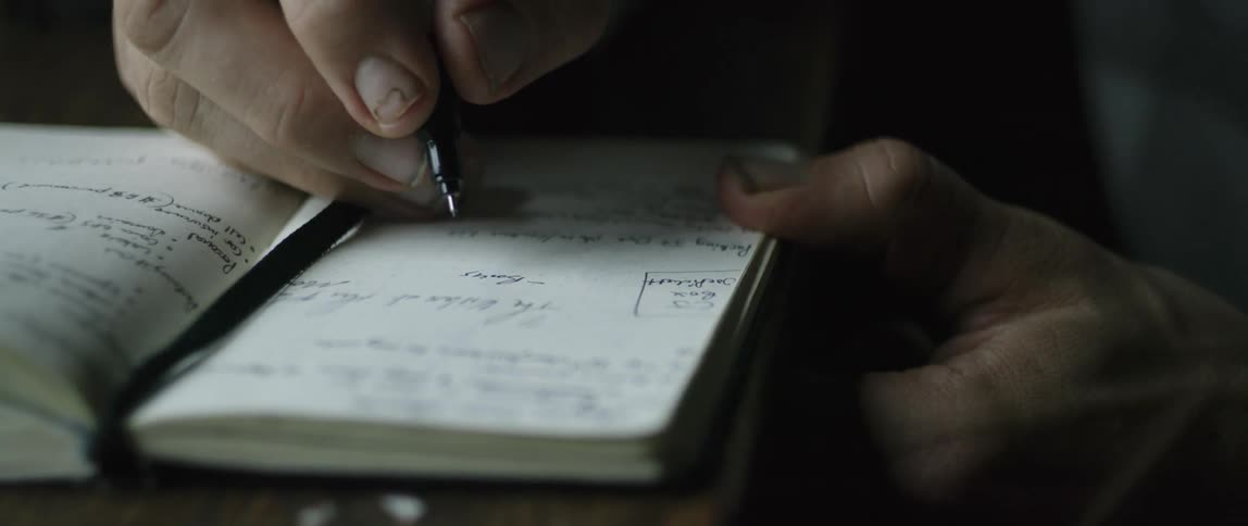 A man writes in a notebook