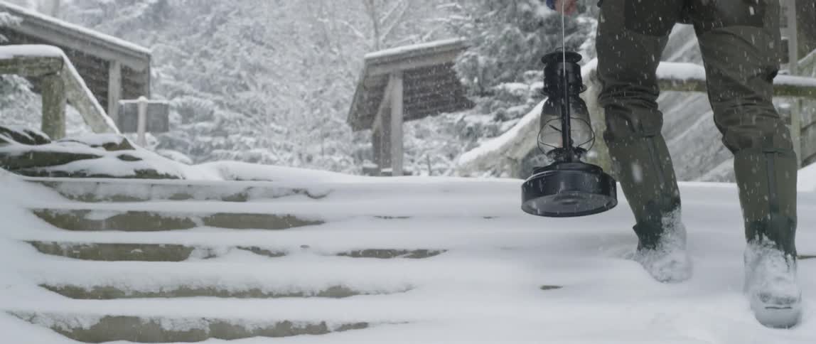 Man carries a lantern in a snowstorm