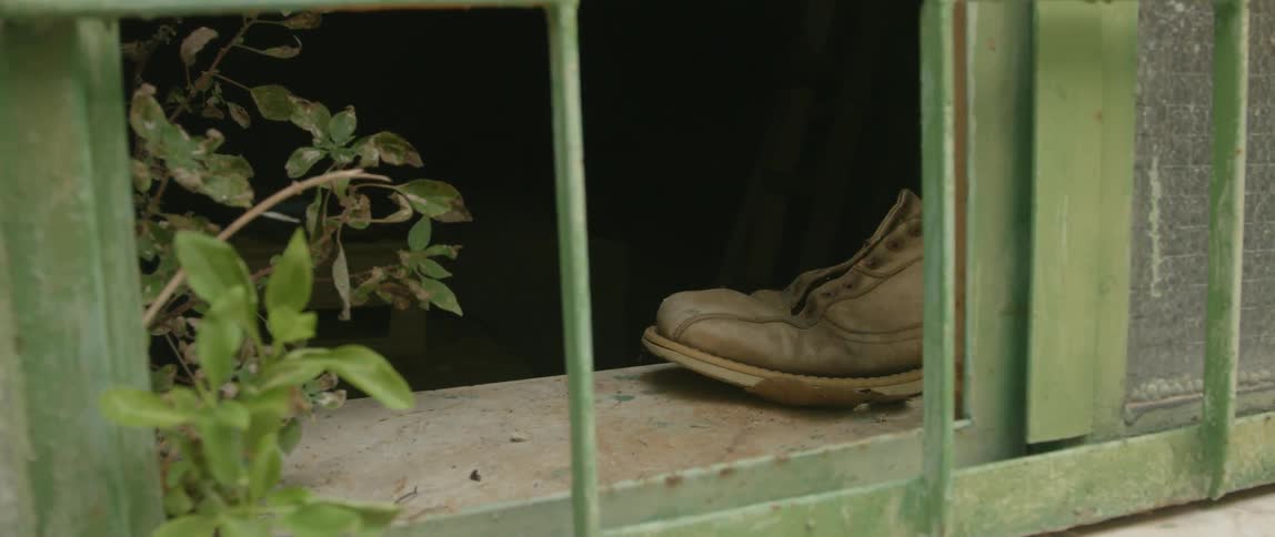 A shoe is sitting by a windowsill