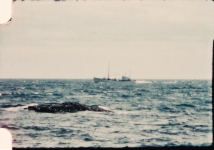 A large boat travels across the ocean during the day