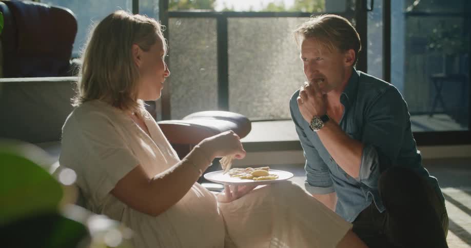 A man and woman snacking and talking