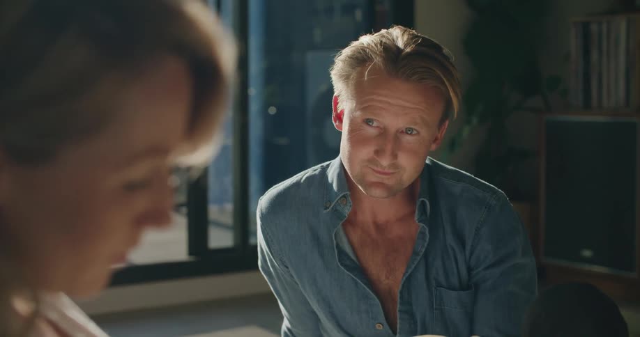 Man looks up from book to smile at pregnant wife who is also reading
