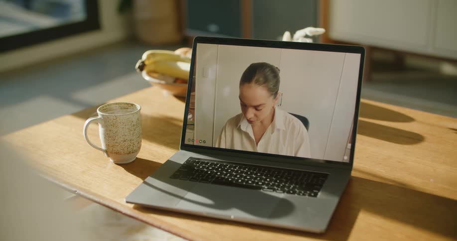 A person uses a laptop to participate in a video conference with a young woman