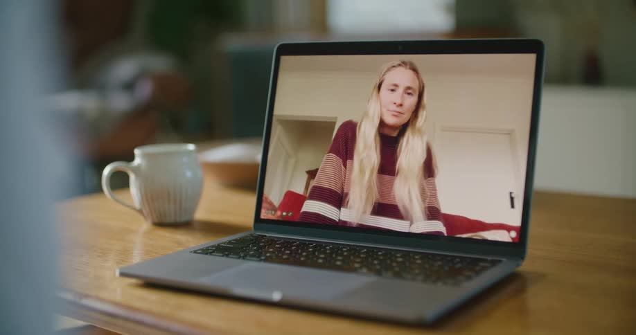 Young blonde long haired woman talking on a video call through a laptop